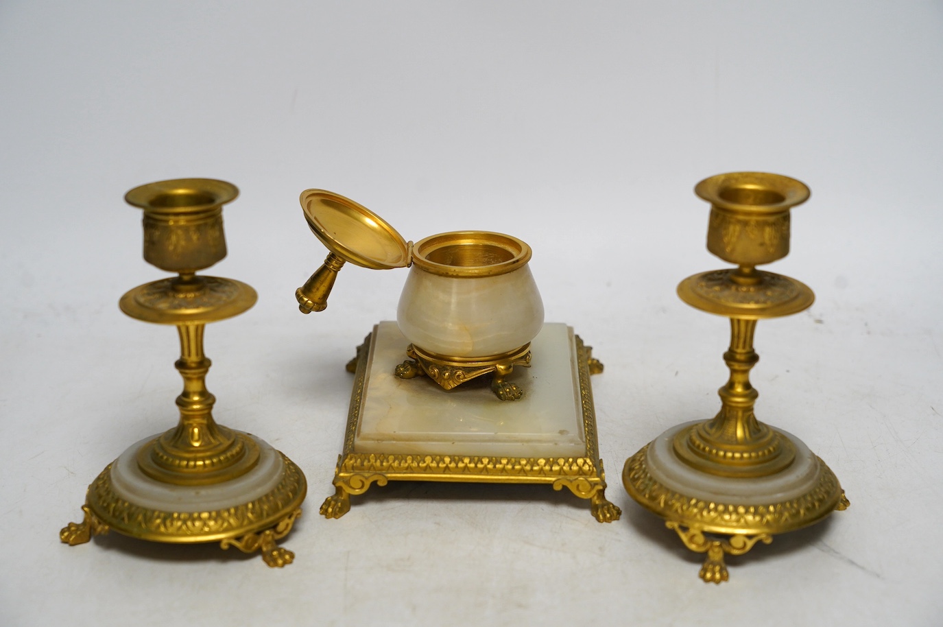 An early 20th century onyx and gilt metal desk set comprising inkwell and a pair of candlesticks, 13.5cm. Condition - fair to good